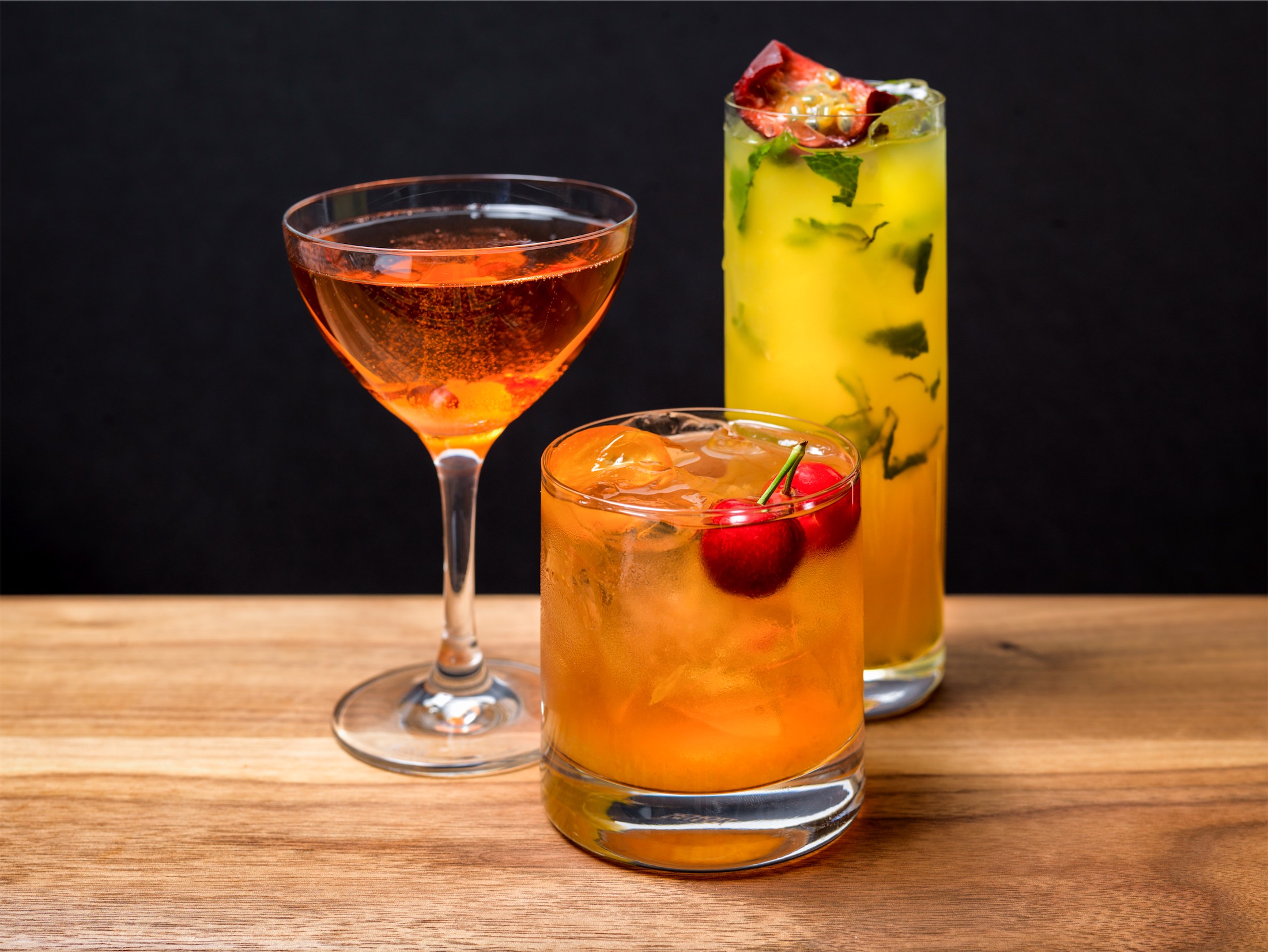 three cocktails on a wooden counter