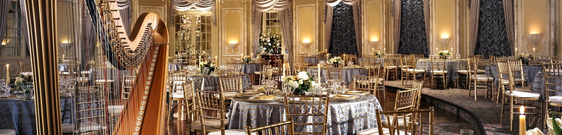 large room set up with round tables and a harp