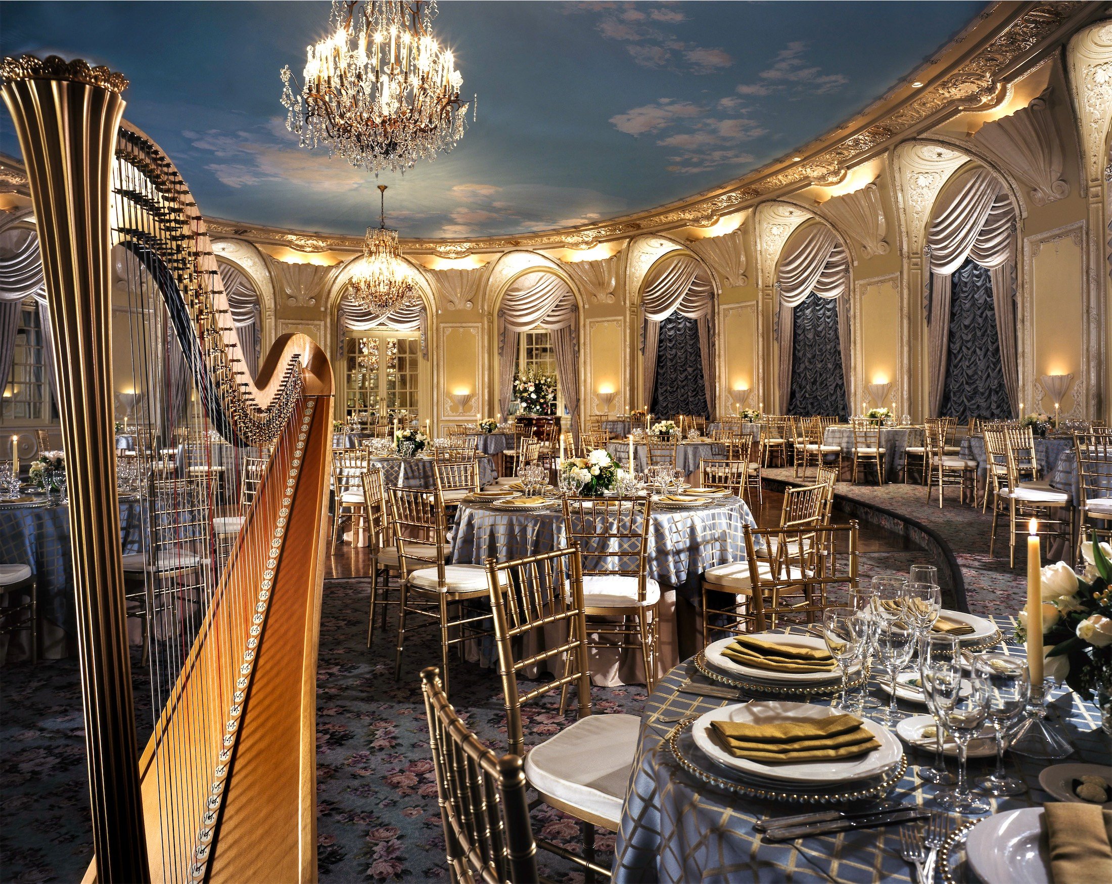 large room set up with round tables and a harp