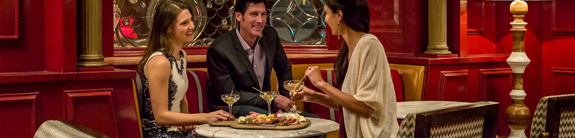 three people eating a charcuterie board and drinking martinis