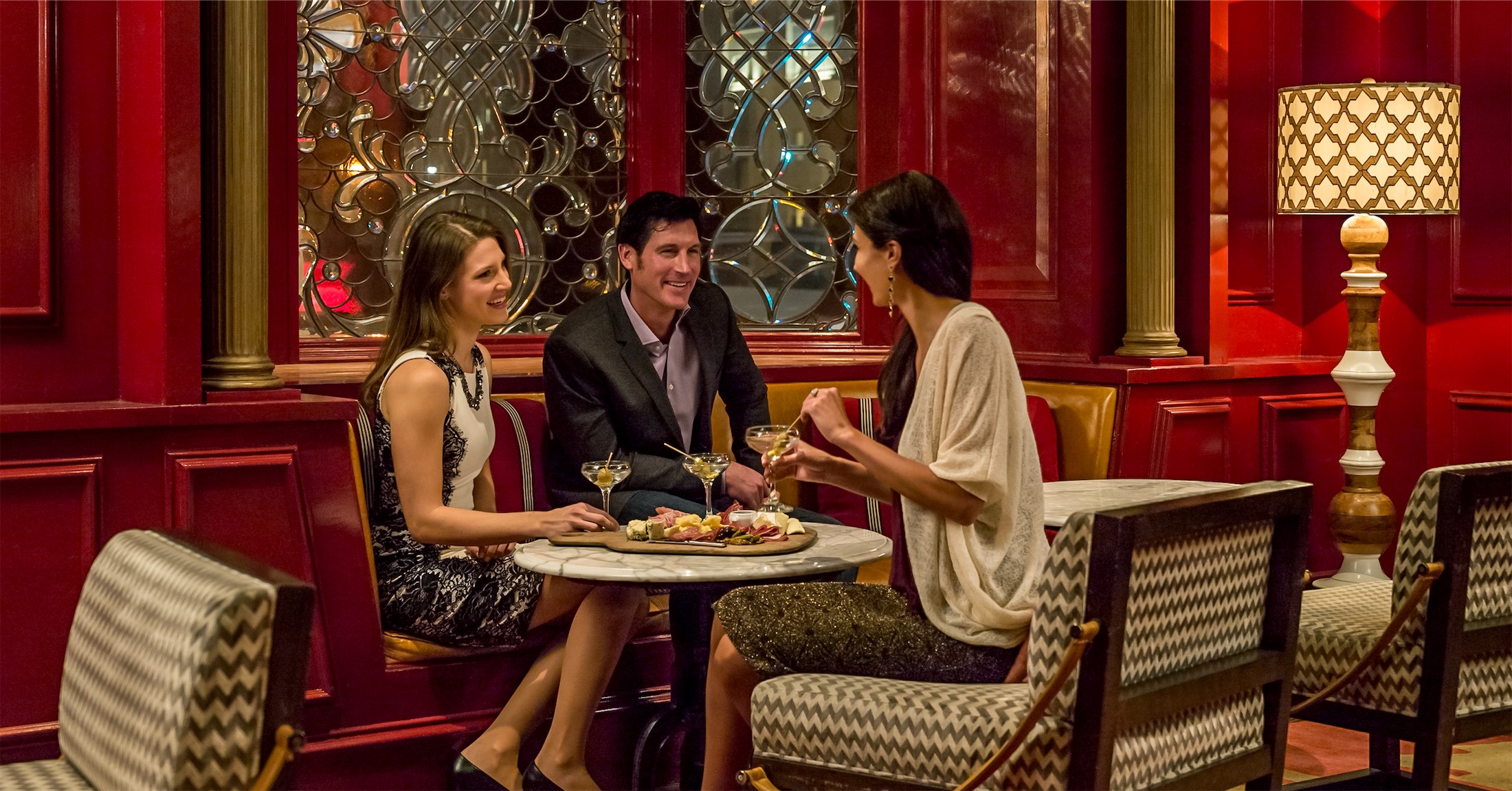 three people eating a charcuterie board and drinking martinis