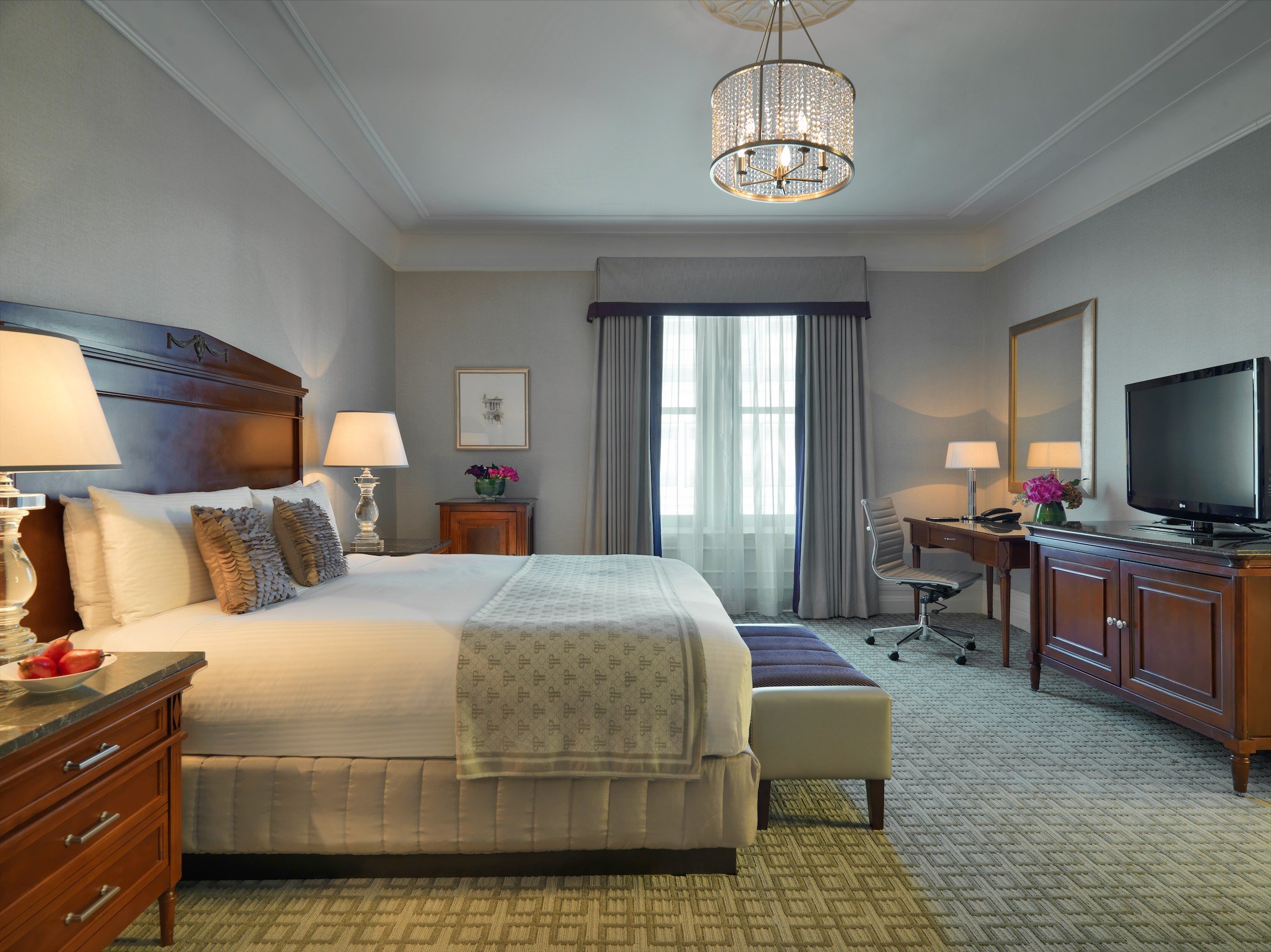 bedroom with small desk and bench at the foot of the bed
