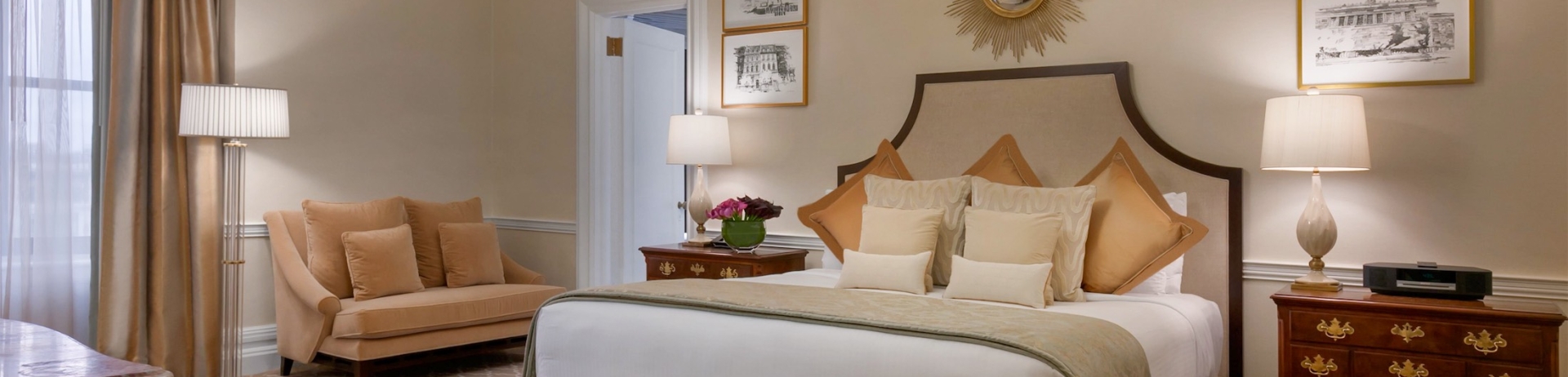 large bedroom with love seat and bench at the foot of the bed