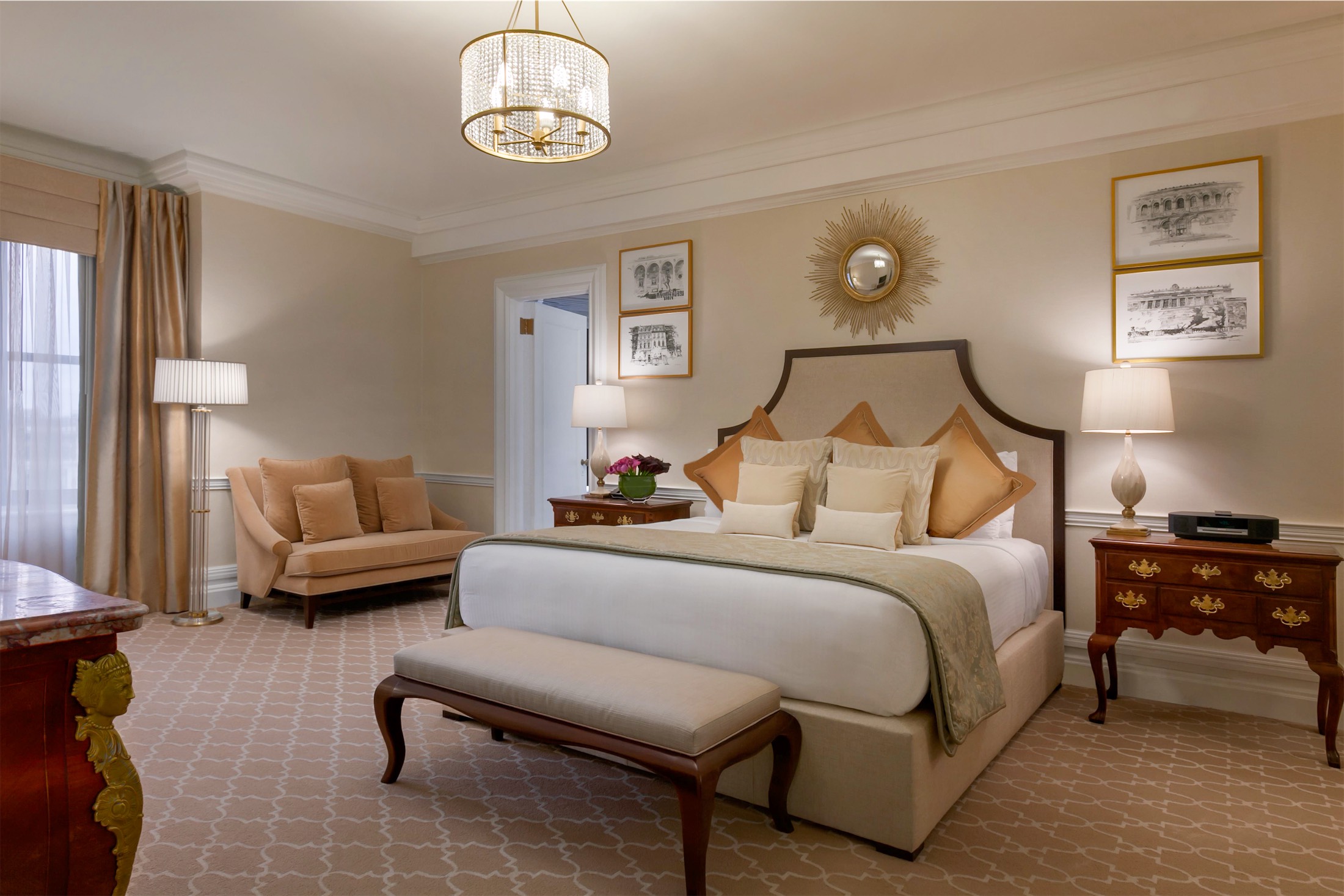large bedroom with love seat and bench at the foot of the bed