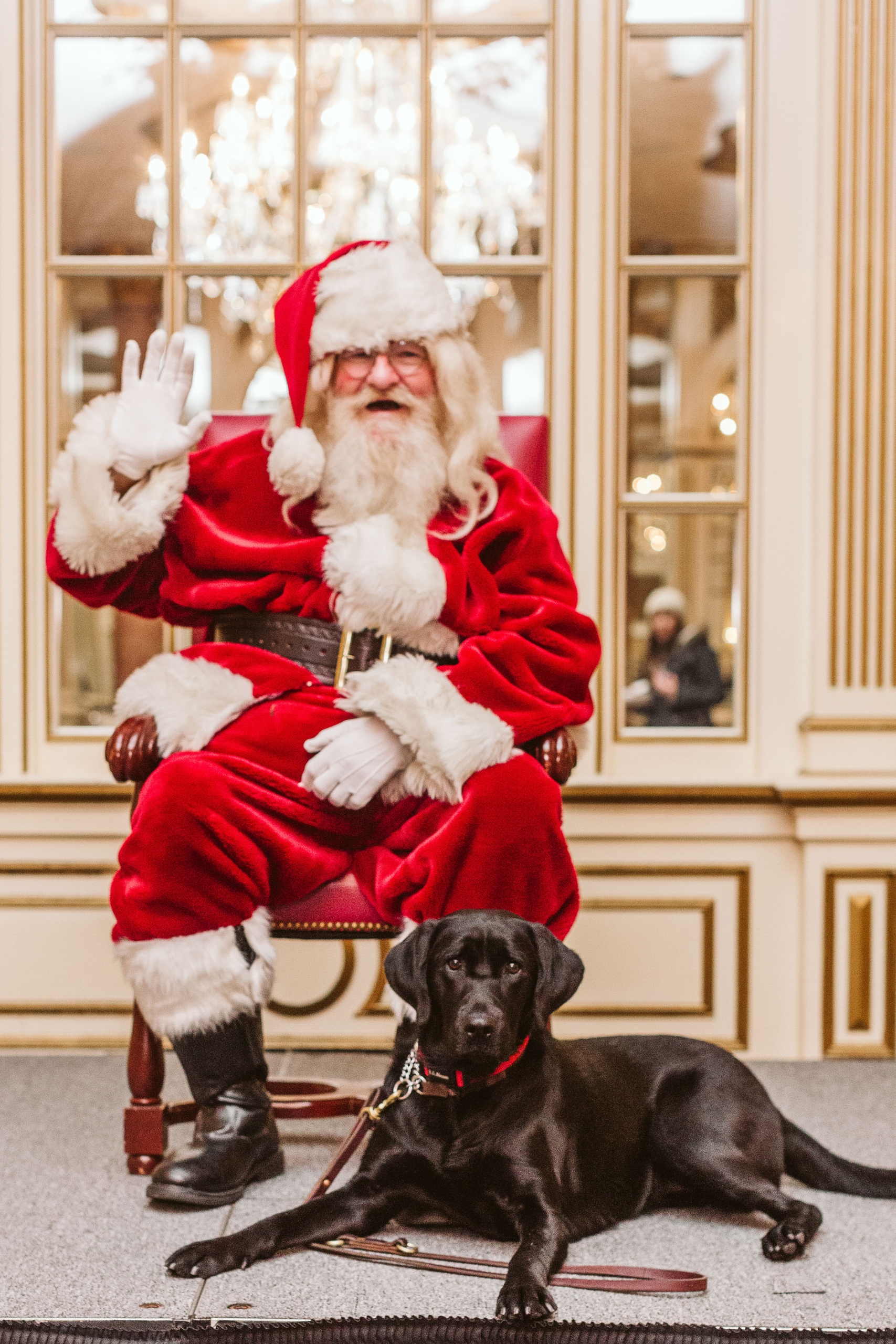 Santa Claus waving with black Labrador at his feet
